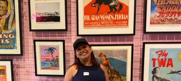 A heritage project student posing in front of framed print.