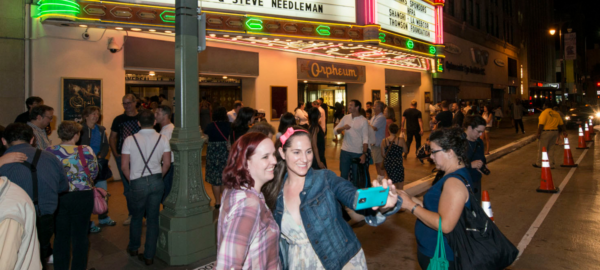 Two people take a selfie in front of the Orpheum Theatre.